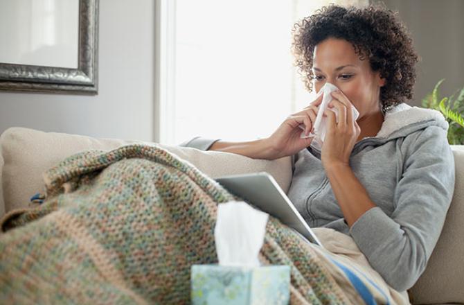 woman on couch blowing nose